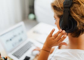 Woman at home using headphones and laptop for online work or video call.